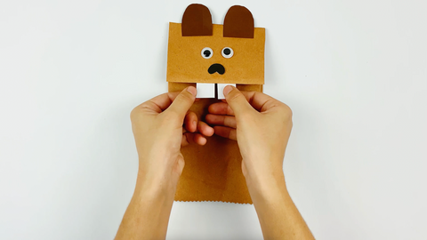 Gluing a face onto a paper bag Canada beaver craft for kids