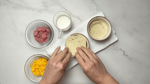 Cook putting bread into ramekins for cheesy oeufs en cocotte