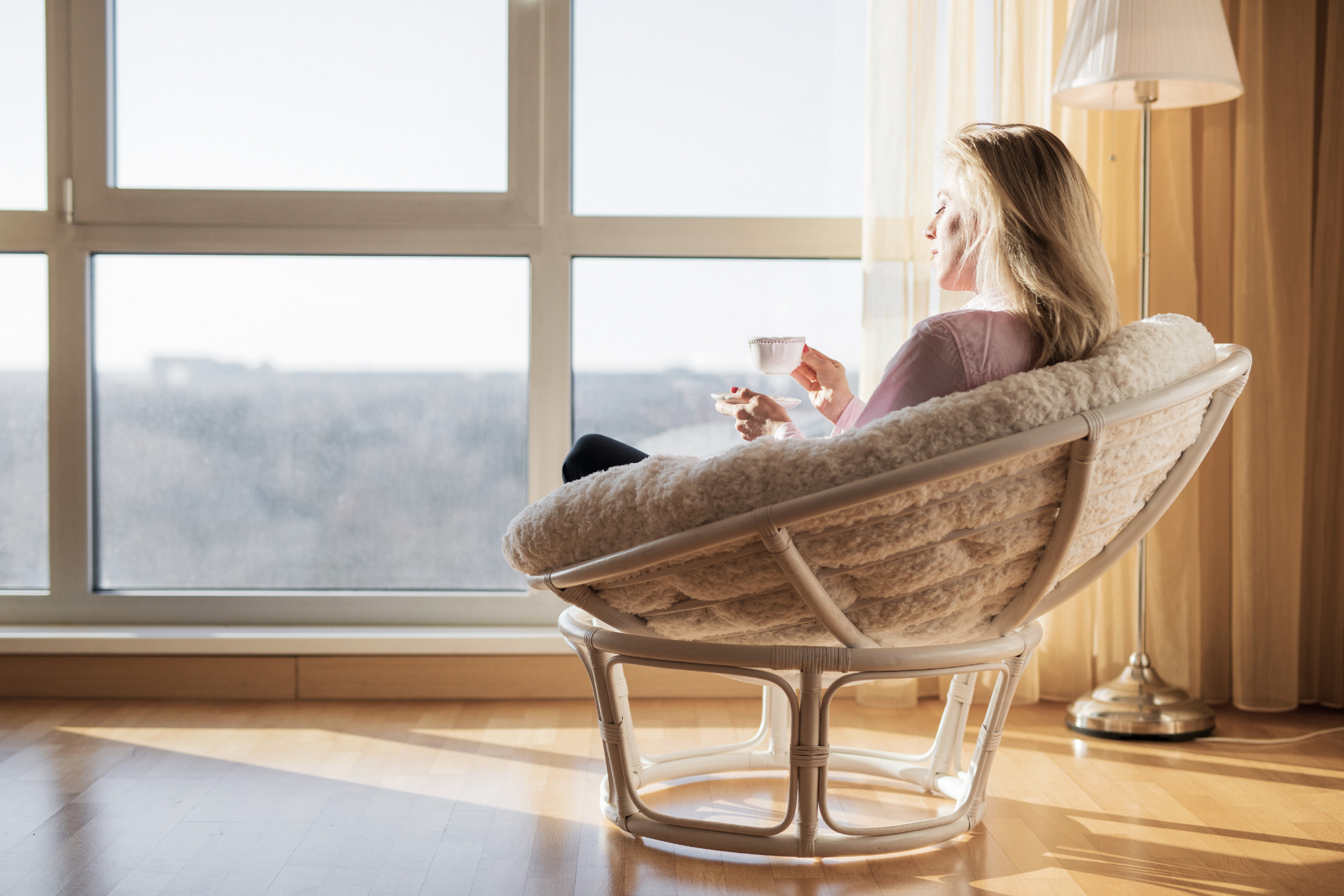 woman with coffee cup looking out her window