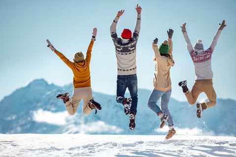 Hommes et femme célébrant devant une montagne enneigée au soleil durant l'hiver