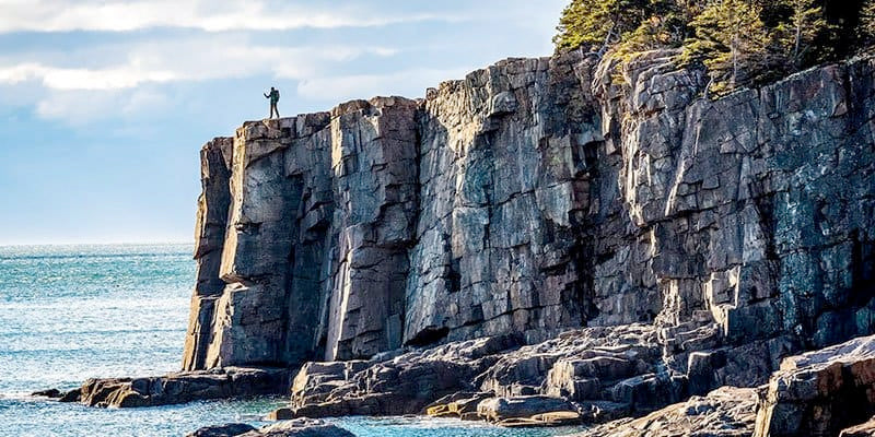 Person standing on rocky cliffs overlooking the ocean