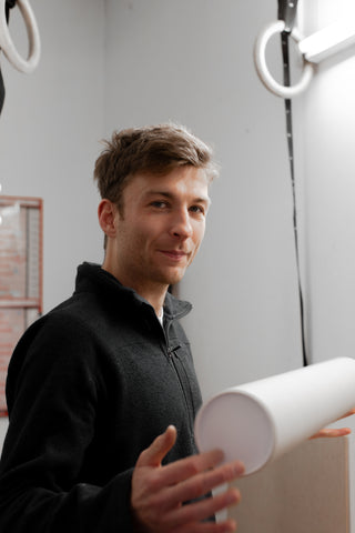 Sam Wood facing the camera holding a rolled up print