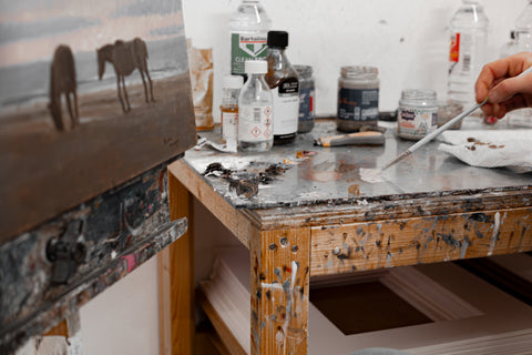 Paint splattered desk with paint brushes and materials