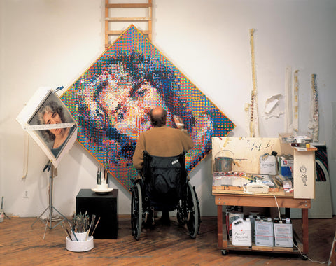 Chuck Close painting from his wheelchair with an easel in front of him