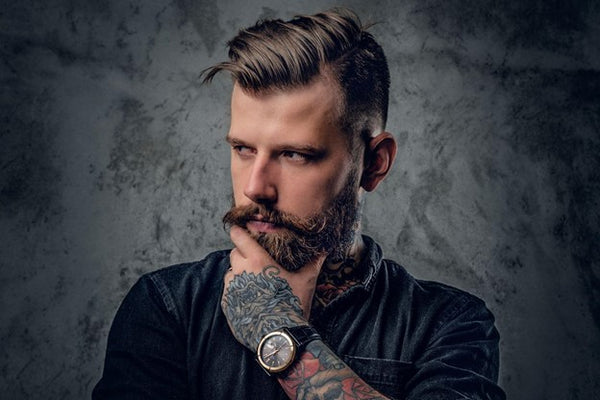 tattooed man holding beard