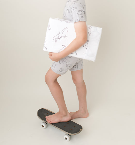 An 8 year old boy carrying brolly sheets products while one foot is on a skateboard