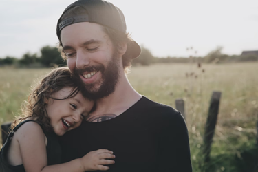 A father and daughter hugging in a field