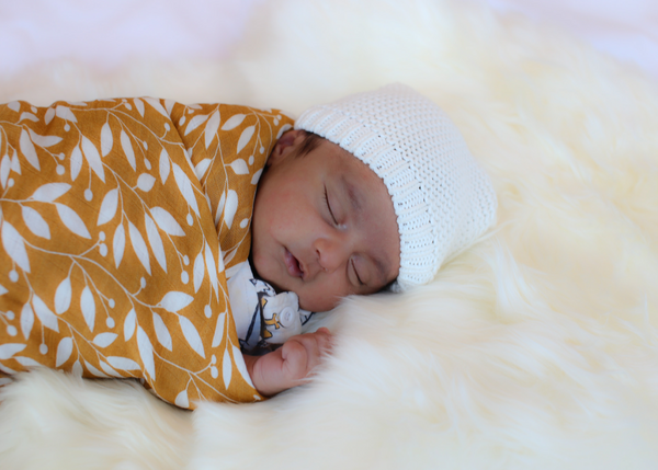 A newborn baby wrapped in a Brolly Sheets Bamboo Swaddle in Autumn Leaves