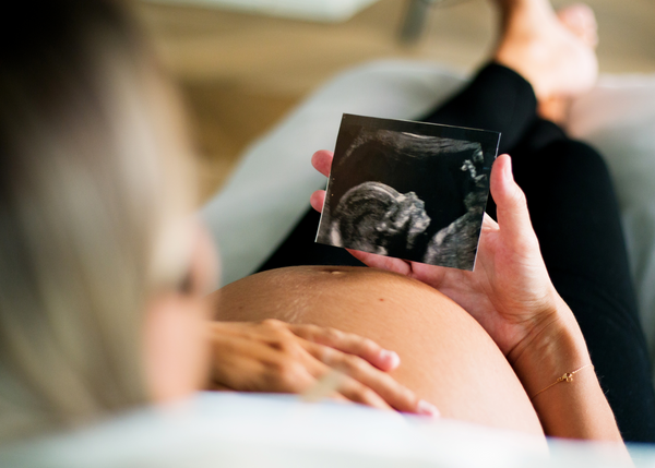 Pregnant woman holding her pregnant tummy and looking at her ultrasound of her baby