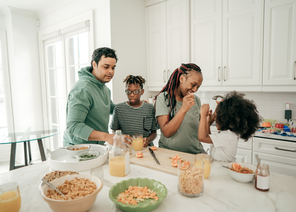 Mum, Dad, son and toddler in kitchen building good behaviour habits around eating food