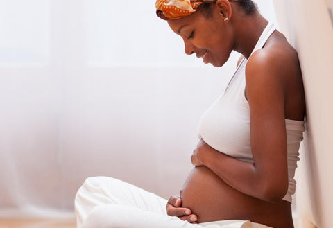 pregnant woman holding stomach and smiling down at it
