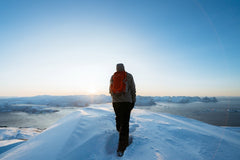 Man with a red backpack walking on a snowy hill