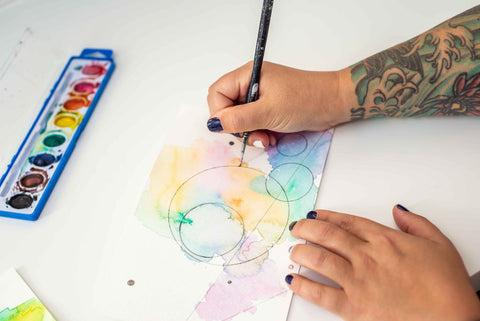 Hands with paintbrush on watercolor painting