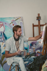 Man sitting in chair painting in home art studio