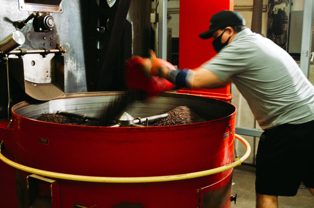 Roastmaster Carlos mixing different coffees to create a blend after the individual coffees have roasted and cooled.