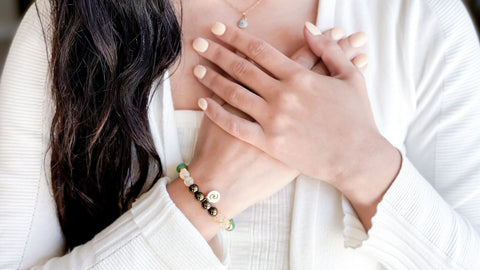 wearing a crystal bracelet on wrist and holding hands to your heart to cleanse crystals