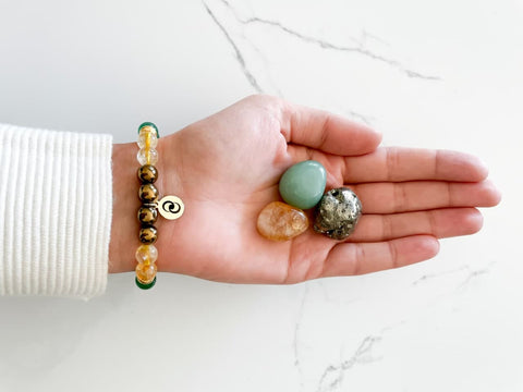 money bracelet on women's wrist and hand holding a pyrite, aventurine, and citrine crystal