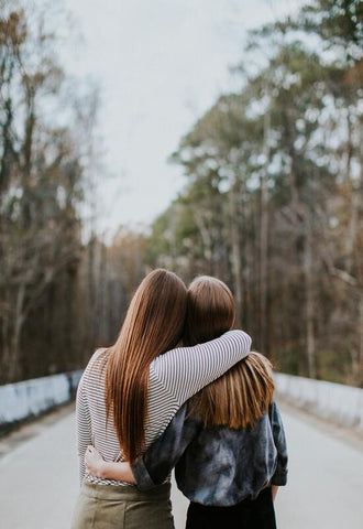 2 women viewed from the back with their arms around each other