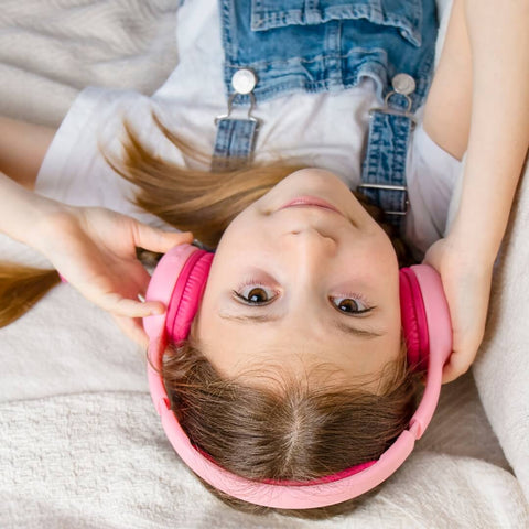 A girl lying down wearing pink headphones