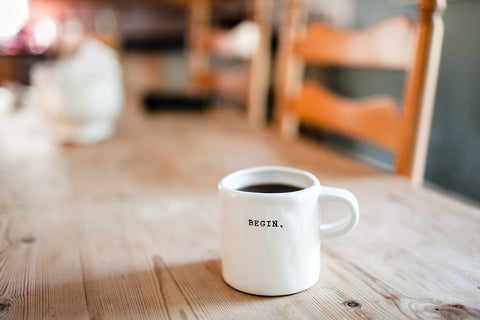 White coffee mug on wood table with begin on it