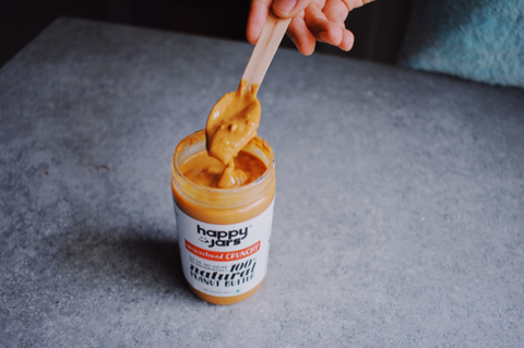 Crunchy texture of the unsweetened peanut butter is shown by digging into a jar of high protein peanut butter by happy jars