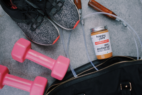 Happy Jars Unsweetened Peanut Butter next to exercise equipment for fitness like skipping rope dumbells and a workout bag used for the gym by diabetic fitness enthusiasts that eat peanut butter