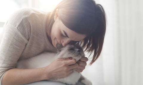 Woman with brown hair cuddling her cat and giving love.