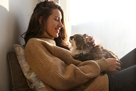 Woman holding her cat while sitting on couch