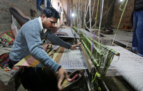Skilled artisan weaving a handmade carpet at Pequra