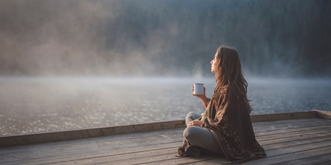 Woman sitting thoughtfully on a dock in the mist