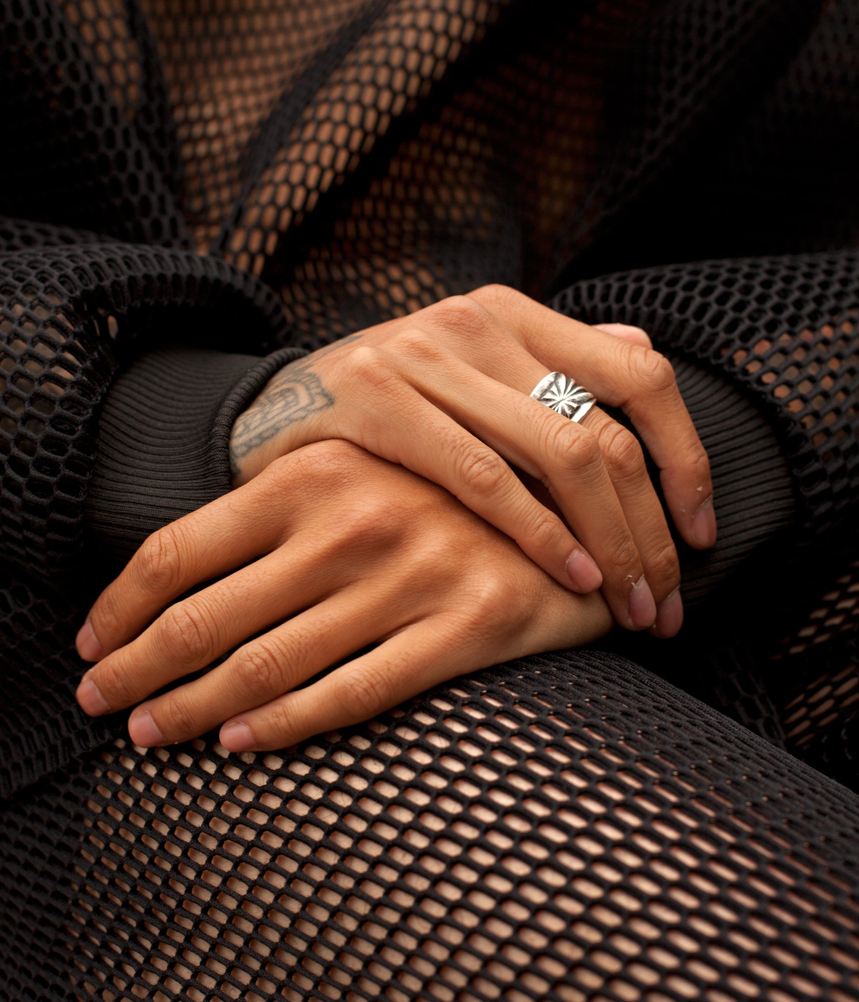 Close up photo of models hands in their lap while wearing the House of Glass Hot Mesh Tracksuit