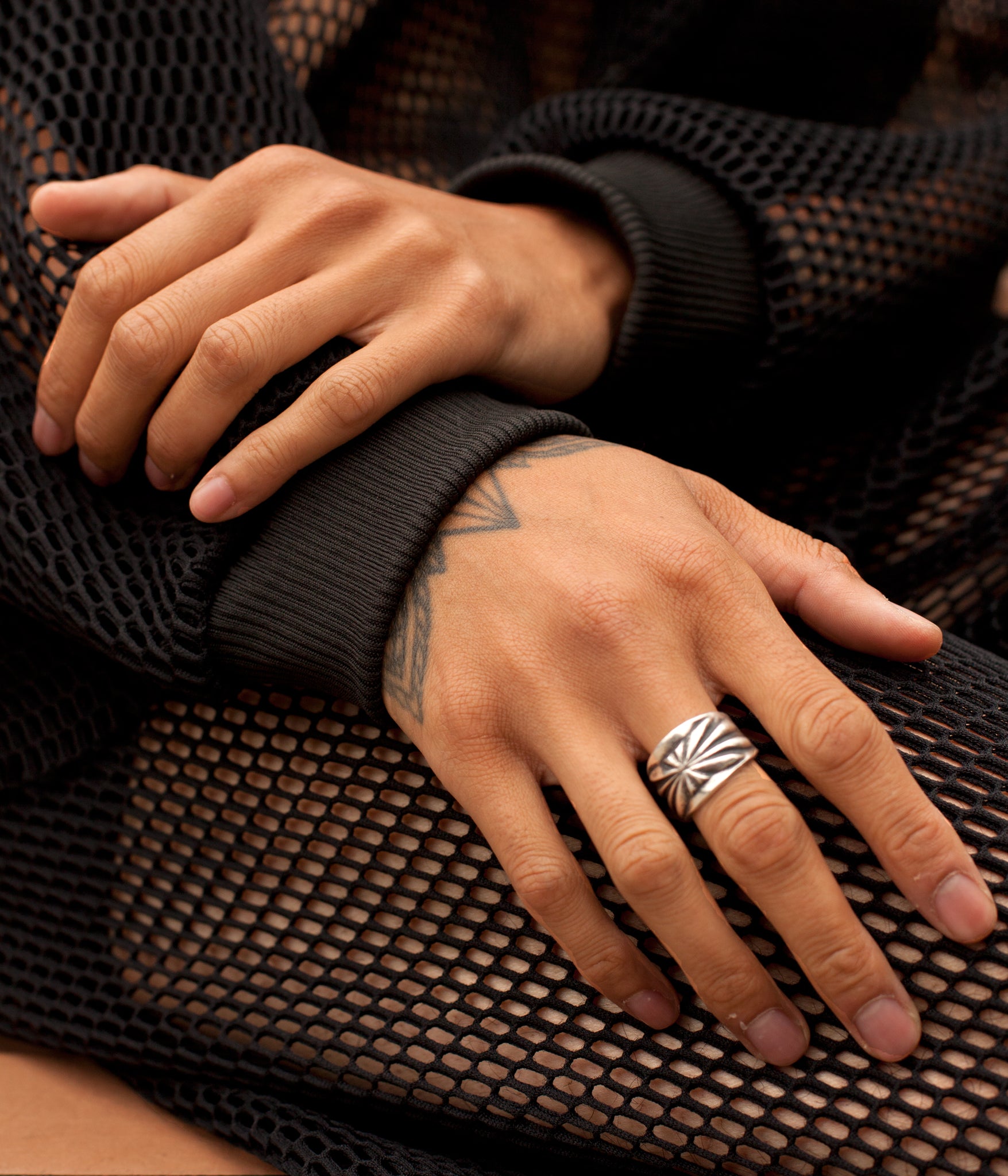 close up photo of models hands in their lap while wearing the House of Glass Hot Mesh Tracksuit