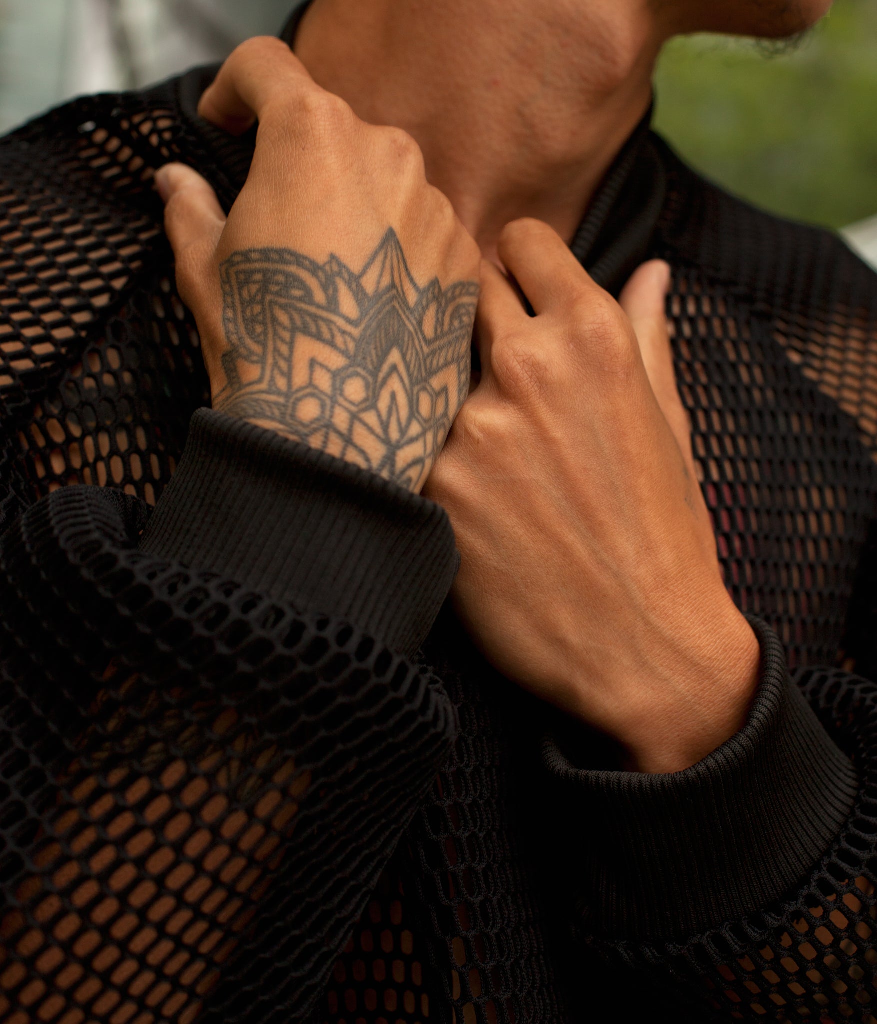 close up image of models hands pulling on the collar of the House of Glass Hot Mesh Tracksuit