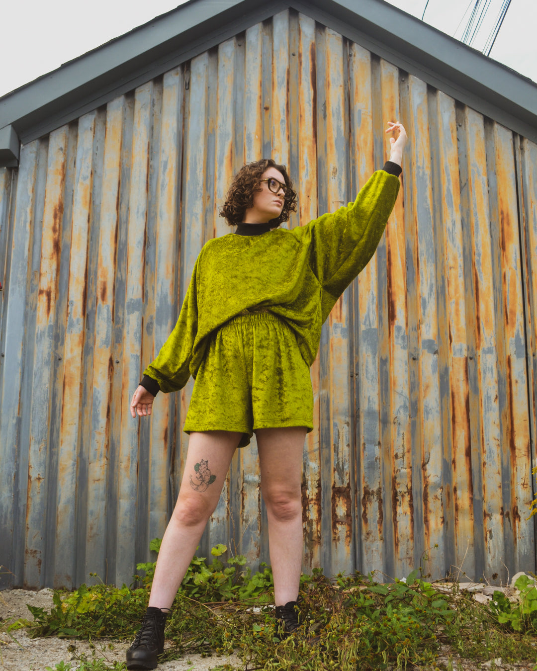 non binary model standing in front of corrugated iron shed wearing the House of Glass Oscar Halfsuit