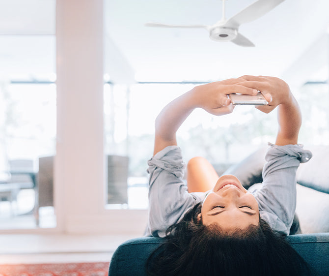 A girl enjoying the wind from a ceiling fan after reading about how it works