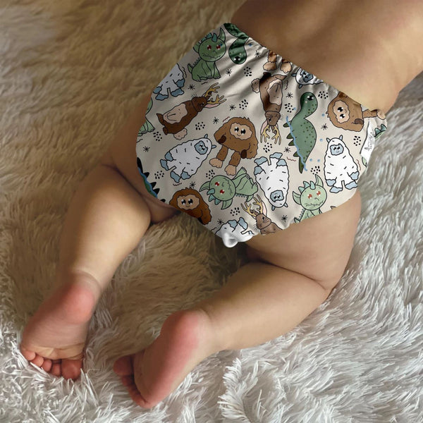 Baby laying on his or her stomach in a white shag rug with a printed cloth diaper on. 