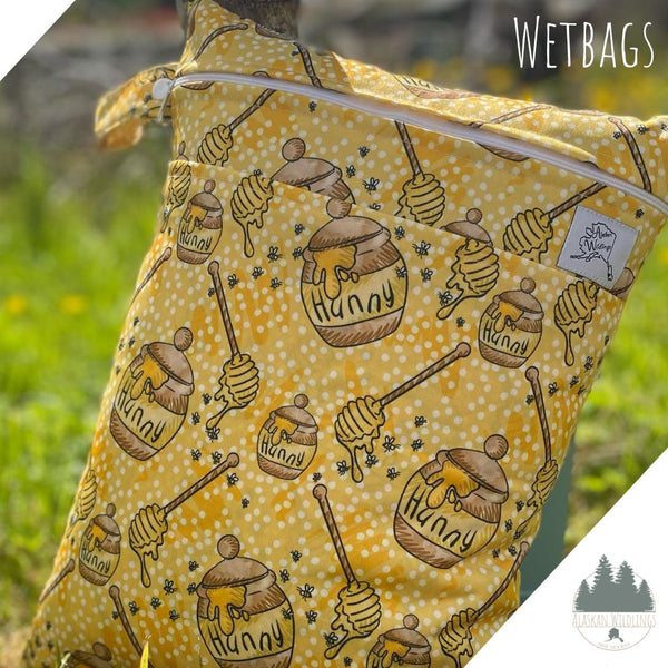 Wetbag with a honey themed print on the grass. 