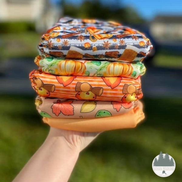 Woman's hand holding a stack of fall-inspired diapers. 