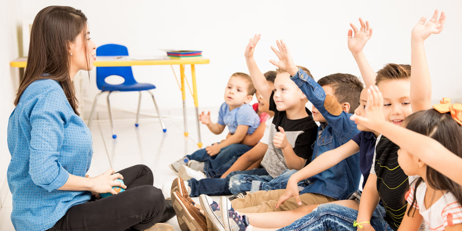 Teacher with preschoolers who are raising their hands in class | Pakapalooza