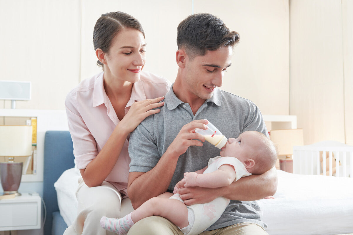 parents looking at baby feeding from a newborn baby bottle