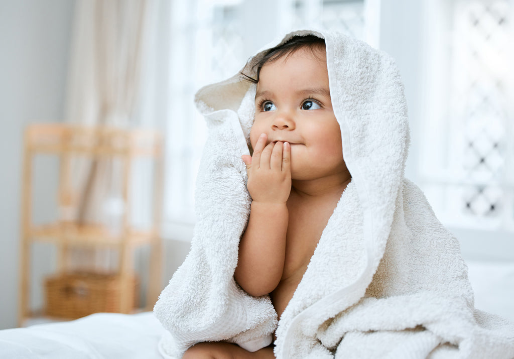 baby sitting with a towel after using baby wash