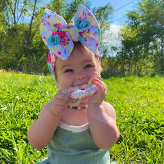 Baby outside chewing on a rattle teether