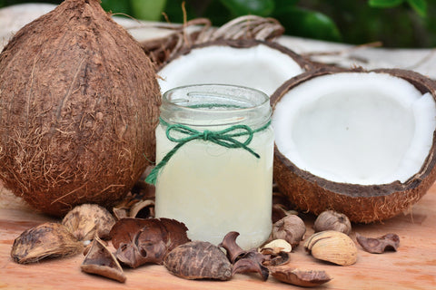 Jar of coconut oil on table top with sliced open coconuts, for Ivy Leaf Skincare blog
