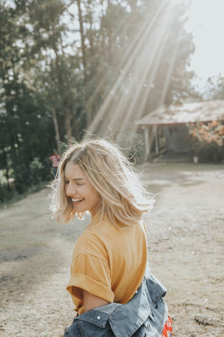Woman outside smiling with eyes closed away from sunshine, for Ivy Leaf Skincare blog