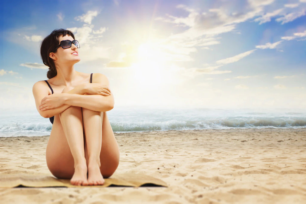 Chica sentada en la playa usando RAW ELEMENTS Natural Sunscreen