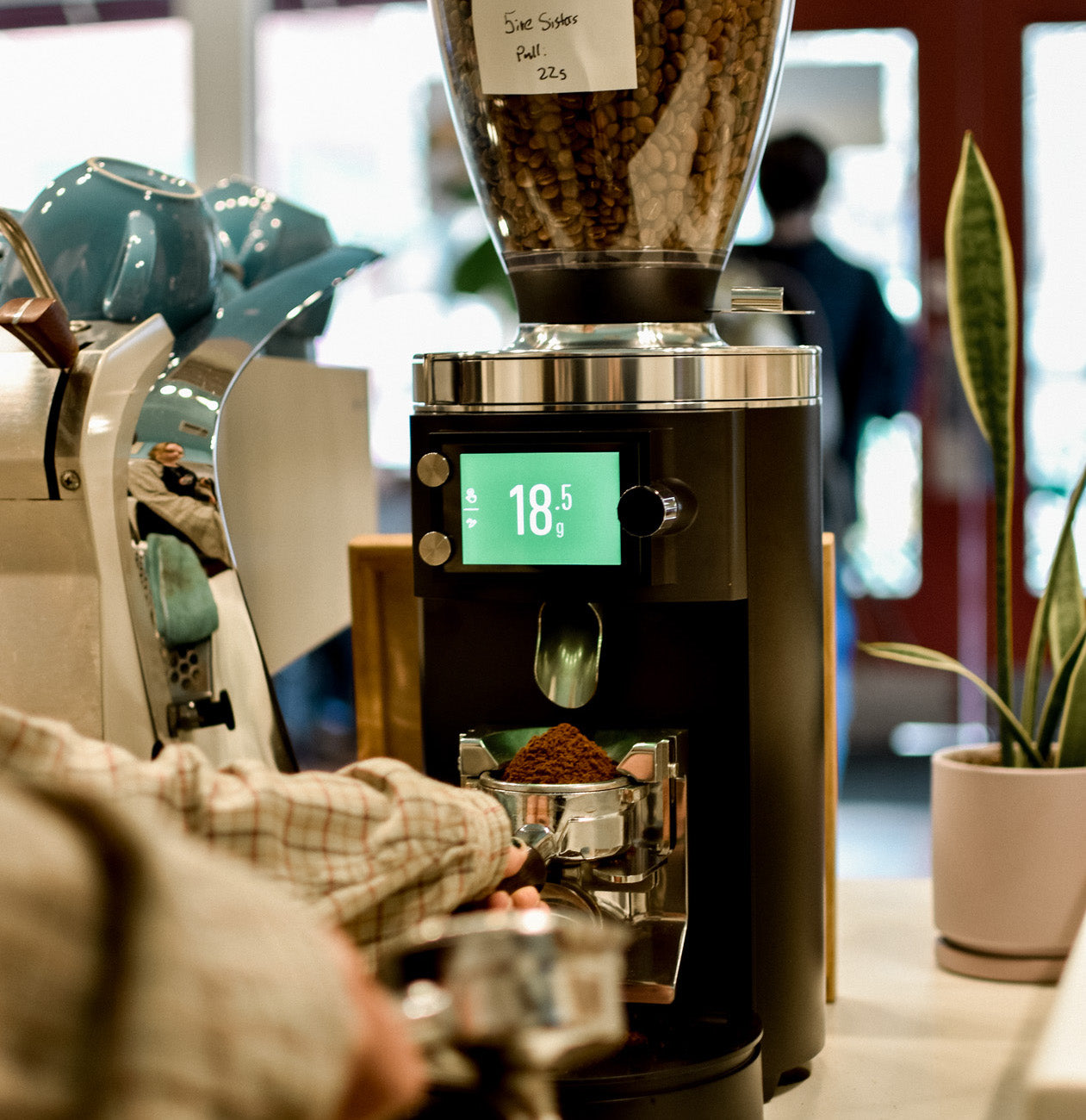 barista using Mahlkonig grinder to weigh out 18.5 grams of coffee for espresso shot