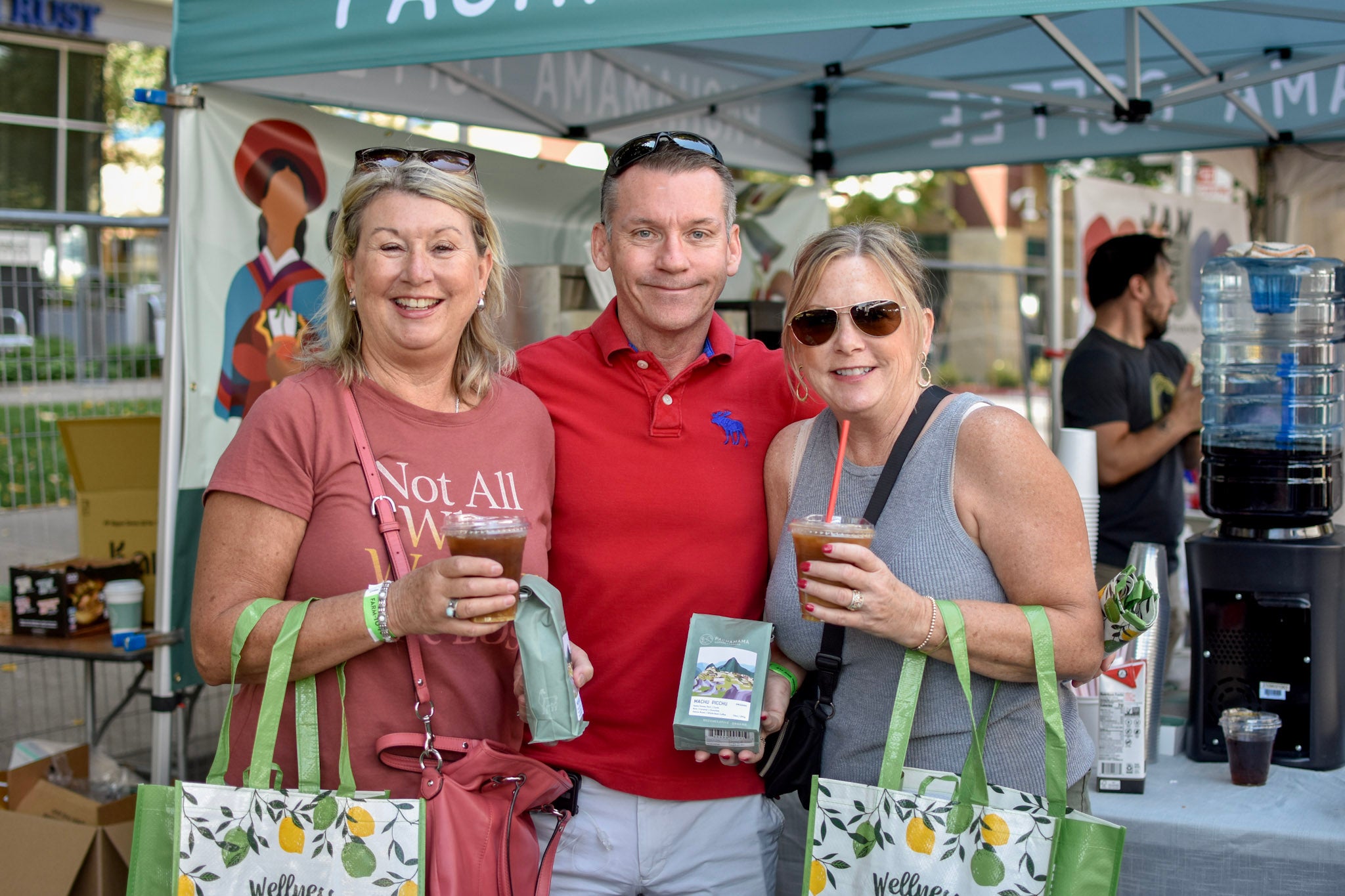 three people smile at camera with coffee bags and drinks