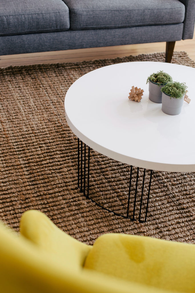 modern white coffee table on metal legs, next to yellow armchair and dark grey sofa made of fabric