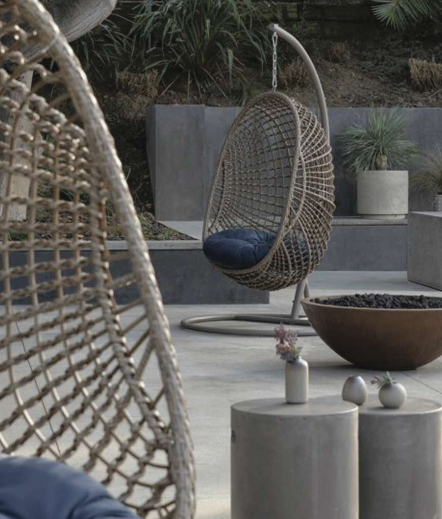 beige hanging egg chair with navy blue cushions on a modern patio