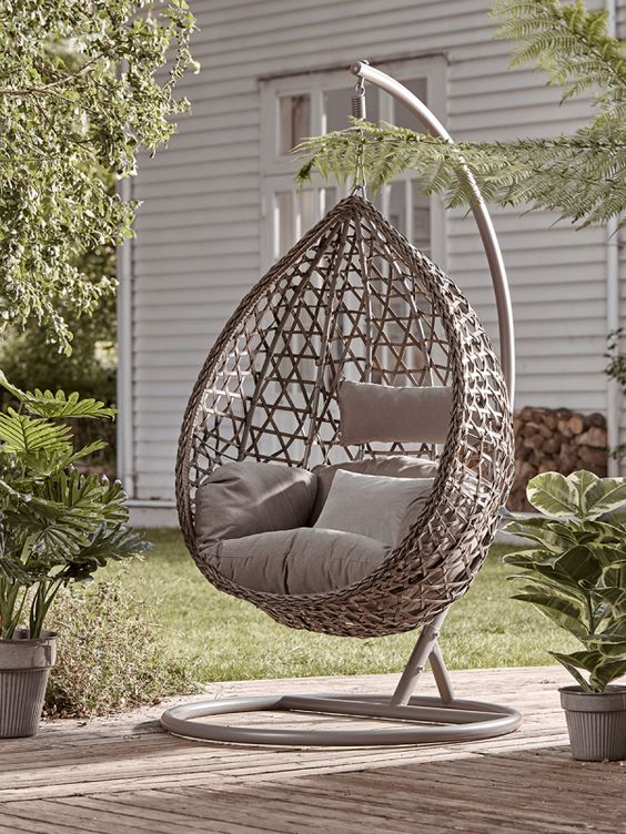 beige hanging egg chair with beige cushions in the garden